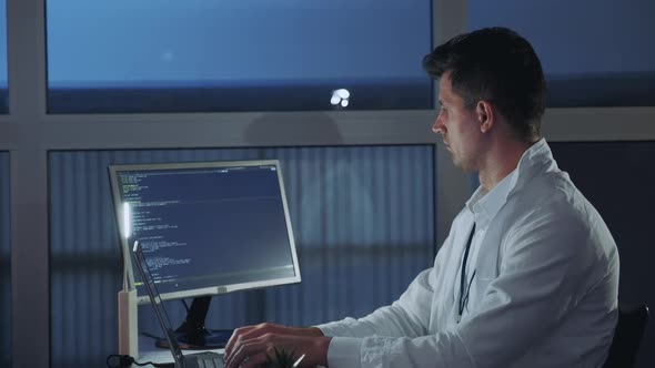 Side View of Young Electronics Engineer Being Engaged in His Research on Computer alt