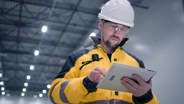 Engineer In Helmets With Tablet Device And Big Paper Drawings Discussing alt