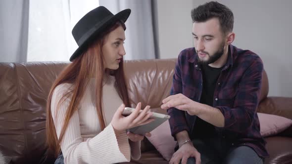 Young Cute Caucasian Woman Irritating As Her Husband or Boyfriend Explaining How To Use Tablet alt