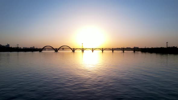 Beautiful sunset, sunrise over the river. Dark silhouette of the arch bridge. Dnipro, Ukraine.