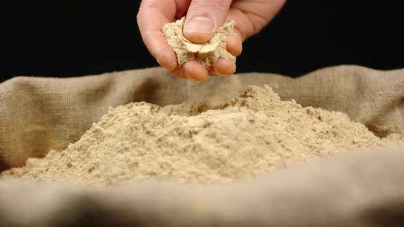 Human hand holds and press a pinch of a ginger powder by a hand over a sac