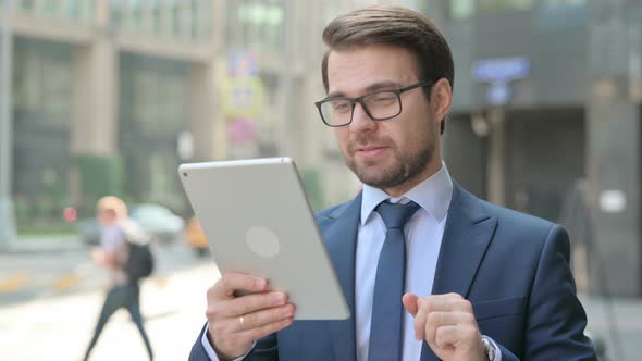 Businessman Talking on Video Call on Tablet in Street alt