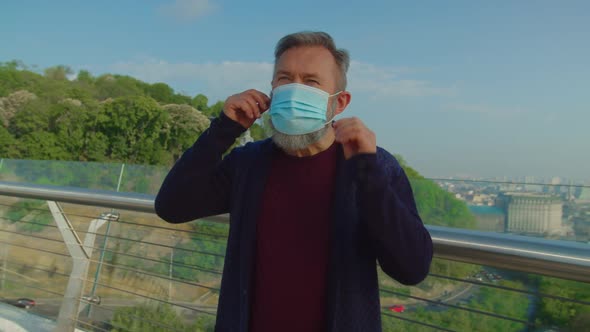 Elderly Vaccinated Man Putting Off Mask and Enjoying Fresh Air alt