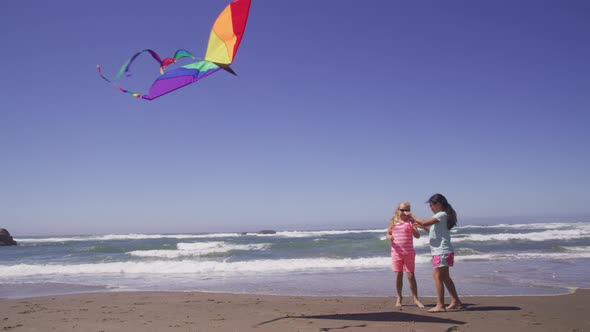 Two young girls playing with kite at beach