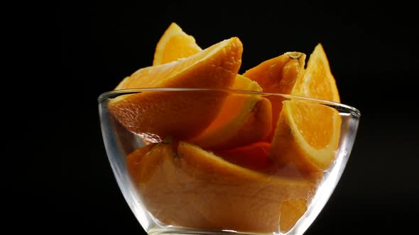 Sweet Orange For Dessert Rotates In A Deep Glass Plate On A Black Background
