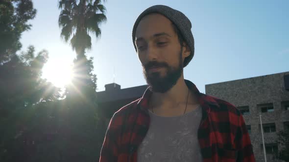 Portrait of a Smiling Skateboarder with a Beard Who Carries a Skate on His Shoulder