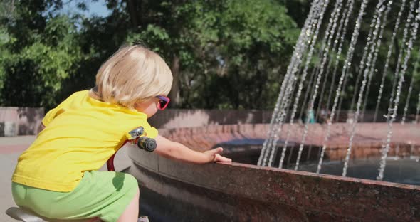 A child touches the water from the fountain with his hand