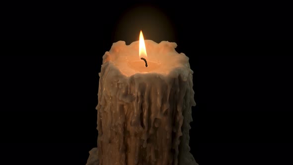 An old and melted candle rotates in front of a black background alt