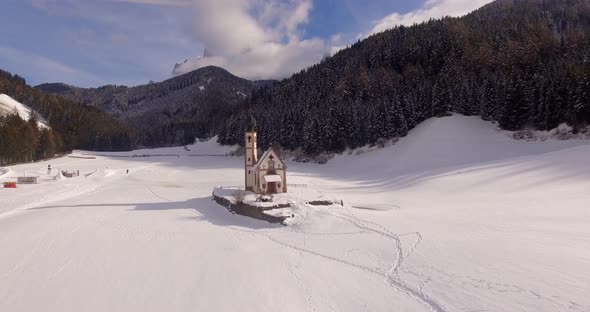 AERIAL: Church with snow in Dolomites in Italy alt