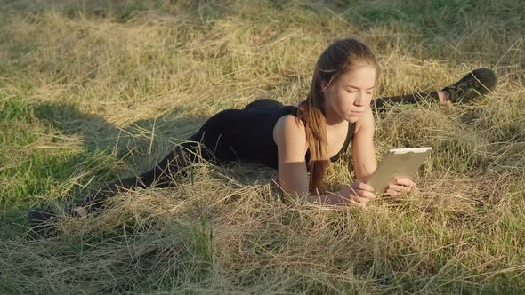 Wide Shot of Young Beautiful Absorbed Woman Sitting in Split and Using Tablet Outdoors. Portrait of alt