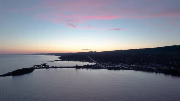 Drone shot of a colorful sunset with active boat harbor alt