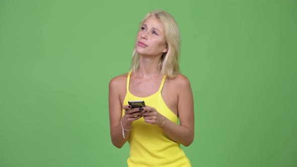 Young Happy Beautiful Blonde Woman Thinking While Using Phone