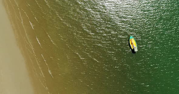 Top view of  small boat on emerald seawater at the beach, aerial drone shot, zooming out