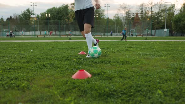 Woman Football Player Practicing on the Grass Field in the the Evening a Freestyler Leads the Ball