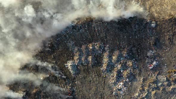 Aerial view of burning garbage pile in trash dump or landfill alt