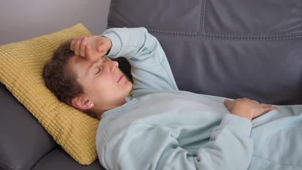 Young Woman on the Couch Touching Her Head Checking If She Has a High Temperature alt