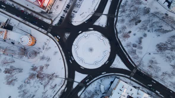 Aerial View of Roundabout Road with Circular Cars in Snow Covered Small European City at Winter Day alt