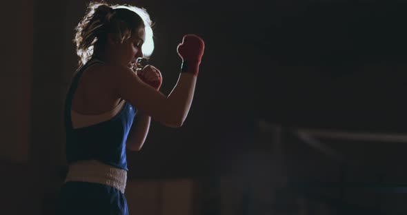 Professional Female Boxer Shoots Off Conducting a Shadow Fight in a Dark Hall Room alt