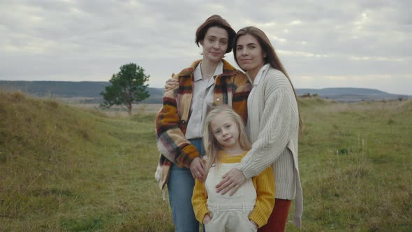 Caucasian Lgbt Family of Three Posing in Embrace Outdoors alt
