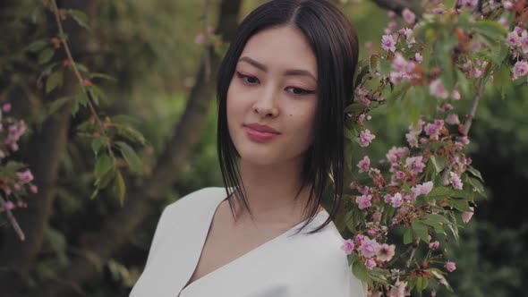 Asian Woman Outdoors on Spring Against Flower Blossom alt
