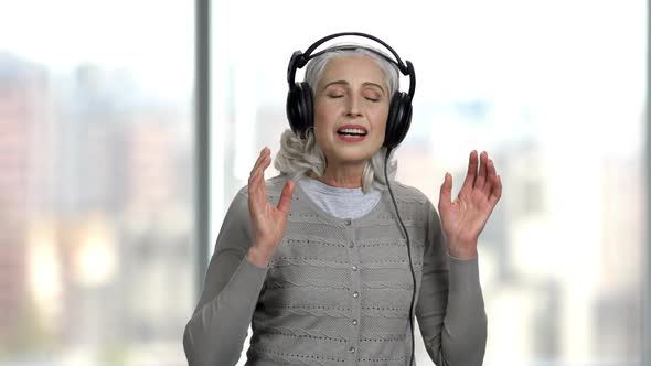 Relaxed Senior Woman in Headphones on Blurred Background. alt