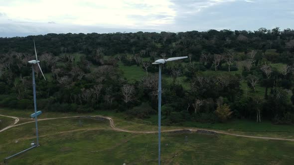 Aerial view of a wind farm situated on a mountain top near the coastline of a tropical island in the alt