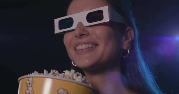 Woman watching a movie with 3D glasses and eating popcorn