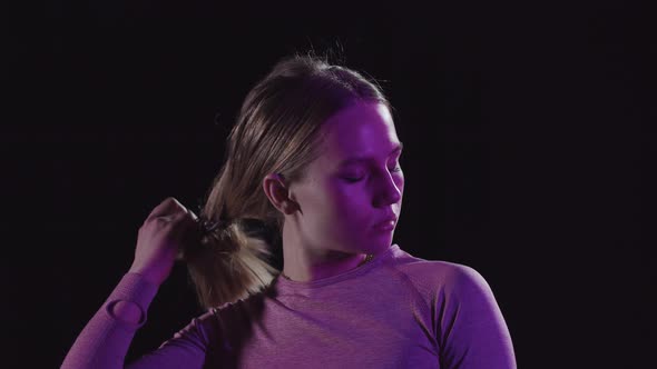Young Woman Spreads Her Hair Out of a Bun and Looks at the Camera alt