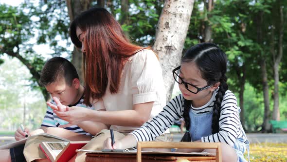 Two children, son, and daughter drawing a picture with family during a picnic in the park