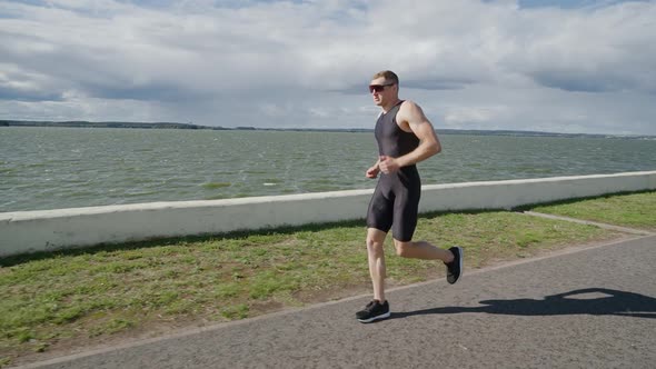 Professional Runner Runs on a Road Near the Lake Athlete Trains in on a Sunny Day Running Before alt