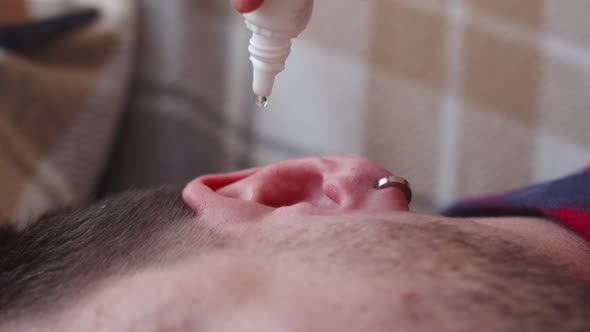 Closeup of Mans Ear in Which Medicine is Dropped From Bottle alt