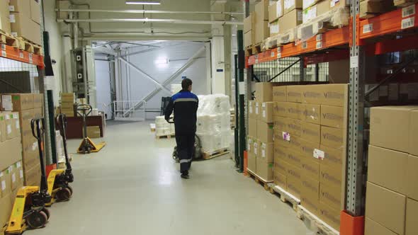 Forklift Operator in Special Uniform is Pulling the Batch of Packaged Containers of Medicine
