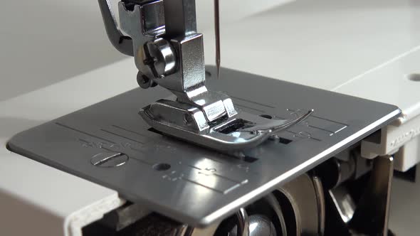 The needle of a sewing machine makes a thread stitch. alt