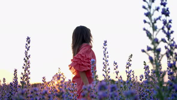 A Young Woman in a Red Dress Enjoying in a Flower Field During Sunset