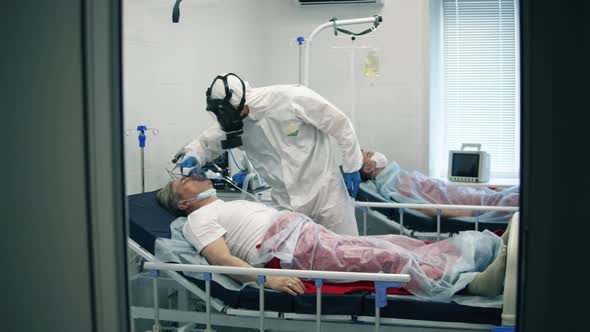 Paramedic Is Checking Temperature of a Man in an Oxygen Mask alt