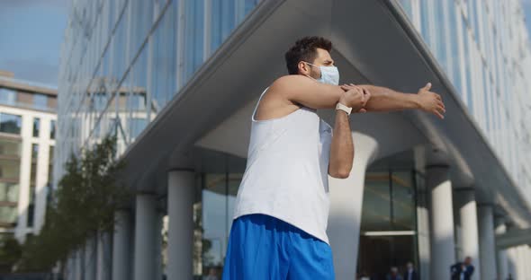 Young Man in Safety Mask Workout Outdoors on City Street alt