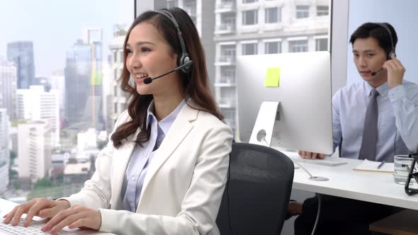 Smiling Asian woman working in Call Center with Chinese man in office