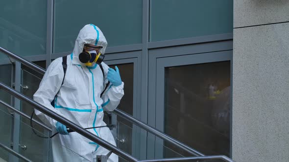 Man in Protective Suit Disinfects Street with an Antiseptic Sprayer. Surface Treatment Due To alt
