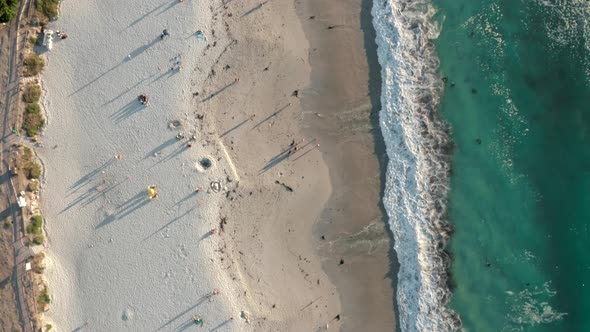 Top Down View Travelling Along the Beach with Blue Waves on the Side