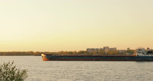 Landscape with great wavy river industrial background on sunset. Barges anchored in the river alt