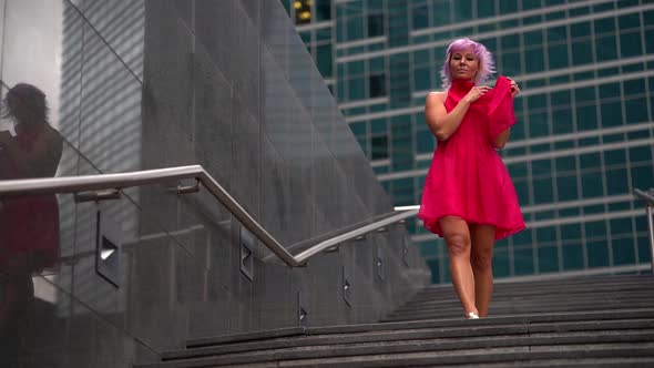Slender Woman in Red Dress Is Walking in Downtown, Full Length Shot alt