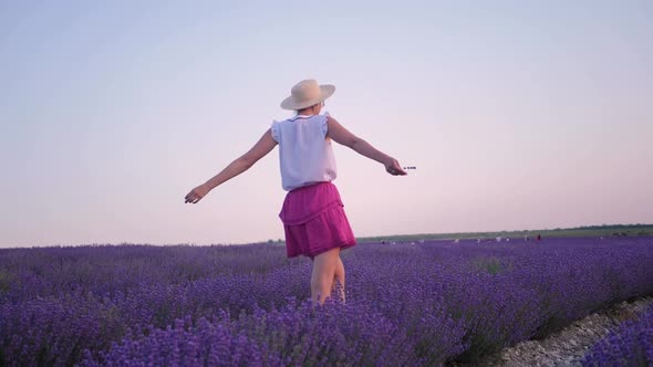 Woman in a Short Purple Dress and a Hat Stands on a Lavender Field alt