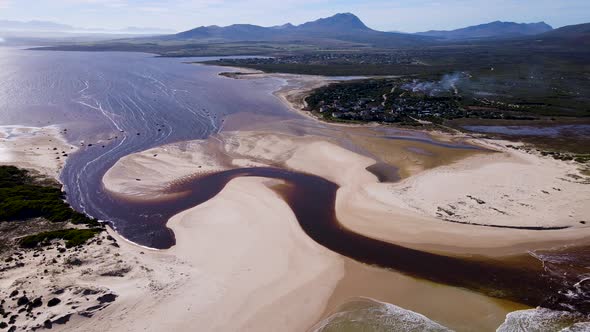Aerial - Flying past Bot River mouth, brown tannin-rich water flows into ocean, Middlevlei, South Af alt