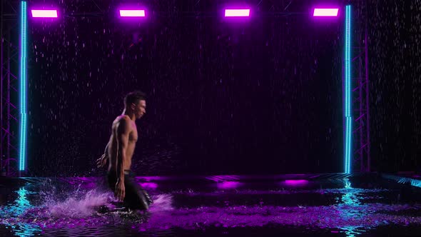 A Wet Man with a Naked Torso Slides on His Knees on the Surface of the Water in the Rain alt