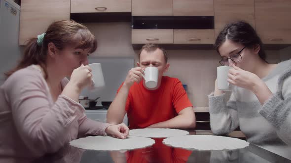 Sad Family Silently Drinking Hot Tea in the Kitchen in the Evening