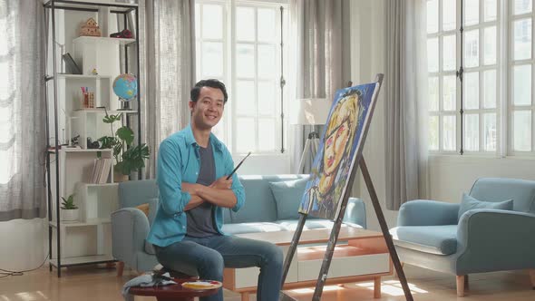 Asian Artist Man Holding Paintbrush Wipe The Sweat Before Crossing His Arms And Smiling alt