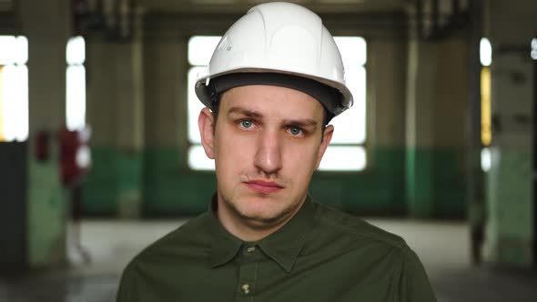 An Engineer in a Helmet Looks at the Camera is Very Sad Upset Failure at Work