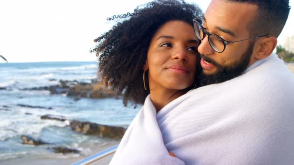 Couple in blanket embracing each other at beach 4k alt