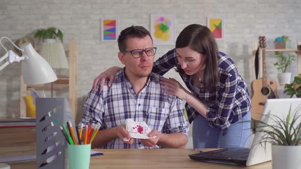 Young Man in Glasses Sitting at Laptop Coughs with Blood His Wife Supports alt