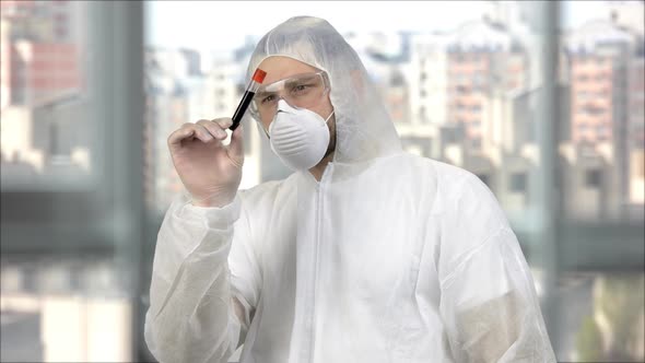 Medical Worker in White Protective Clothing and Mask Holding Test Tube with Blood alt